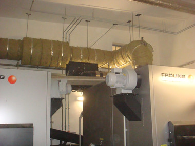 Insulated industrial HVAC ducts and machinery mounted in a factory setting.