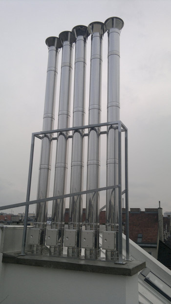 Five tall cylindrical rooftop vent pipes with rounded caps mounted on a metal frame.