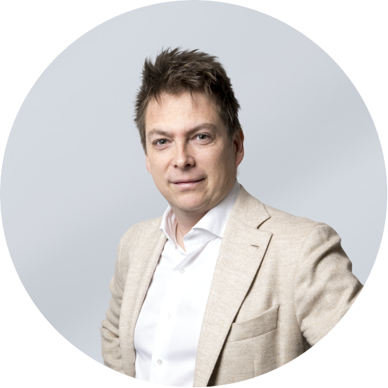 Portrait of a man in a beige blazer and white shirt against a light gray background.